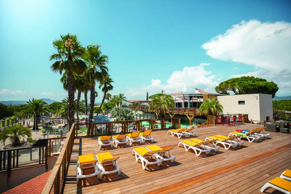 Plage de piscine en bois au niveau du solarium de l'espace aquatique d'un camping